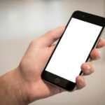 selective focus photography of person holding iphone displaying white screen